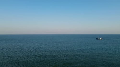 A fishing boat sails on the calm Baltic Sea, the rolling sea and clear sky on the horizon, Hel Polan