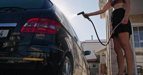 Woman Washing Car in Suburban Driveway