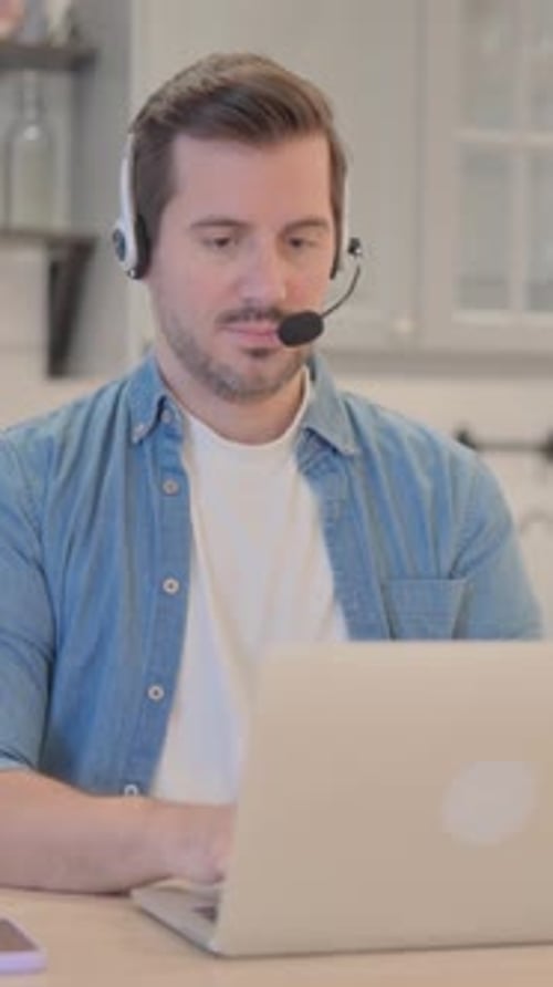 Young Man with Headset Working on Laptop, vertical video