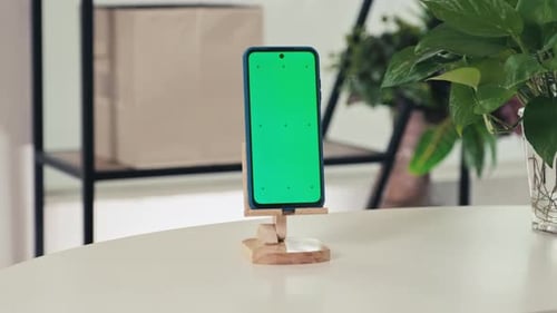 Smartphone with Green Chroma Key Screen in Wooden Stand on Table in Living Room