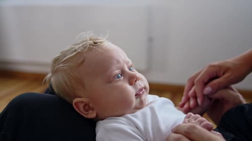 Blonde Haired Baby Lying on a Parent's Lap