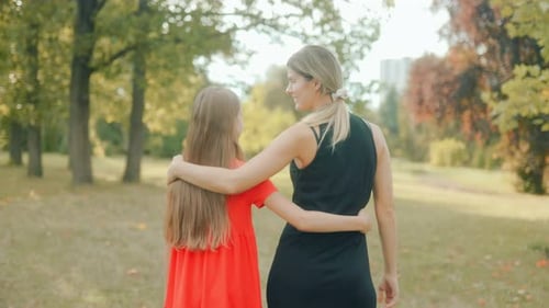 Girl and Woman Hugging Lovingly While Walking Together in Green Park