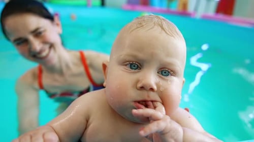 Close Up of Baby Swimming with Adult in Pool
