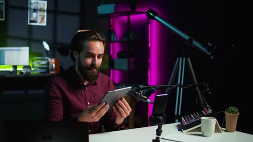 Man Comparing Tablet to Mobile Phone on Tripod