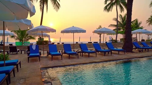 bed pool and umbrella around swimming pool with sunset or sunrise sky