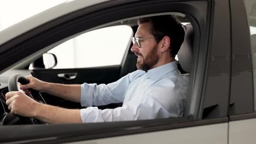 Smiling Businessman Test Driving Car at Dealership