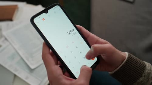 Hands of Anonymous Man Counting Monthly Payments on Calculator App on Smartphone