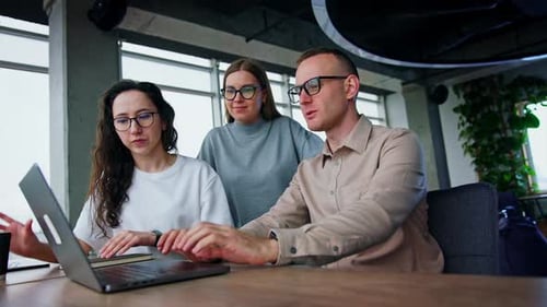 Team Gathers Around Laptop in Modern Office