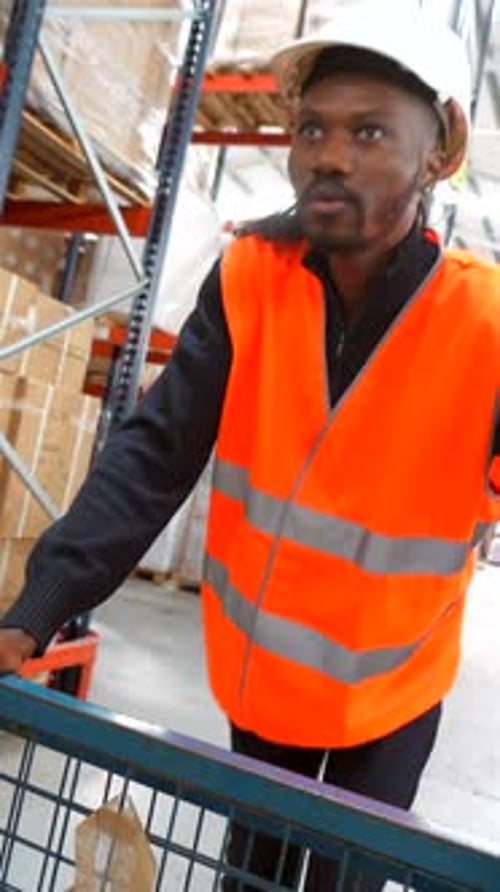 Logistics Operator Pushing a Trolley in Warehouse