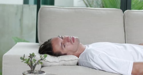 Tired Man Falls on the Sofa at Home After a Hard Day's Work and Suffers From Headache and Overwork