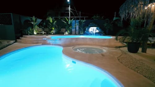 Luxus-Hotelpool mit Jacuzzi und Wasserfall bei Nacht