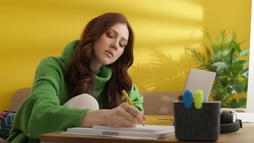 Young Woman Writing in Notebook at Home