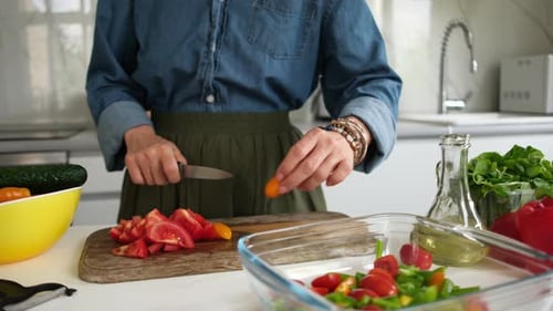Woman cutting vegetables for salad in bright kitchen