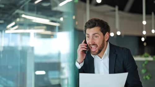 Man Holds Documents and Talks on Cell Phone in Office