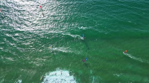 Aerial view from the sun reflected at sea with several windsurfers enjoying the good conditions of