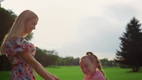 Smiling Mother and Daughter Playing at Green Meadow in Sunset Time. Joyful