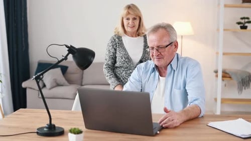 Man showing something to the woman. Couple of cute old people that is indoors at home