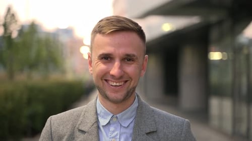 Jeune homme d'affaires souriant regardant la caméra dans la ville Ralenti