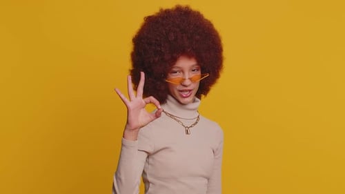 Young Funny School Girl in Glasses Looking Approvingly at Camera Showing Okey Gesture Like Sign