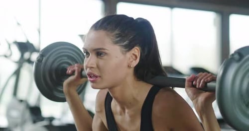 A beautiful smiling woman trains at the gym with both sports equipment and free body to keep fit a