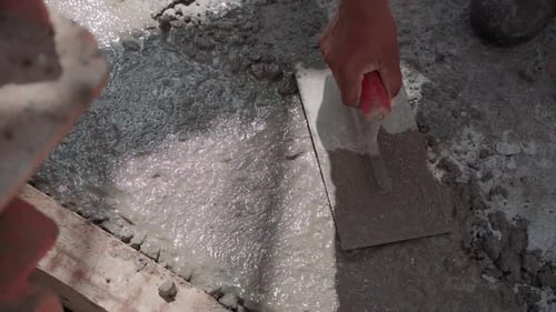 Slow motion of a worker levelling concrete on the floor with a trowel.