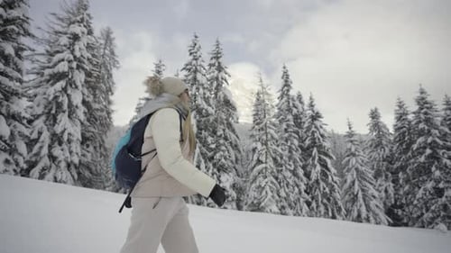 Woman Hiking Through Snowy Winter Forest Landscape