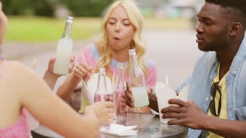 Friends enjoy takeout and drinks at outdoor table