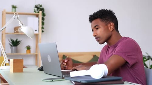 Young Man Studying with Laptop at Desk Indoors