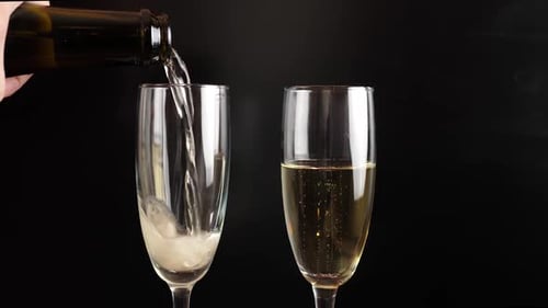 Champagne Poured into Champagne Flutes Against Black Background