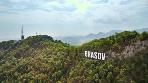 Brasov sign with tourists on the top of the hill near the city, green trees around, Romania. Old cit