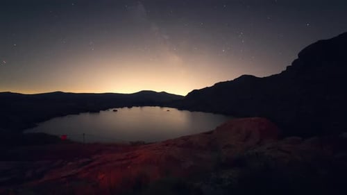 Night timelapse of the Milky Way and stars above Laguna Grande de Peñalara in Sierra de Guadarrama,