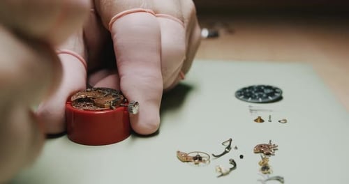 A watchmaker carefully removing parts of a watch for repairing and cleaning - Close up