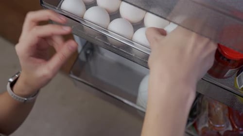 Hand taking egg from refrigerator door shelf
