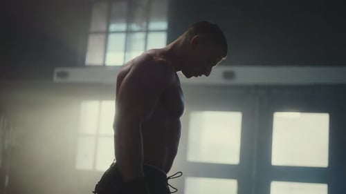 Muscular Man Working Out with Dumbbells in Gym
