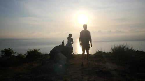 Couple Traveler at a Cliff with the View of Sunrise and Ocean Horizon