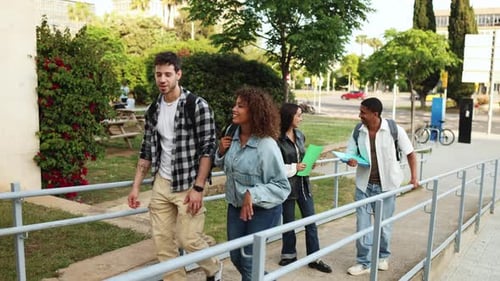 Diverse students walk and laugh on a college campus, holding books and backpacks