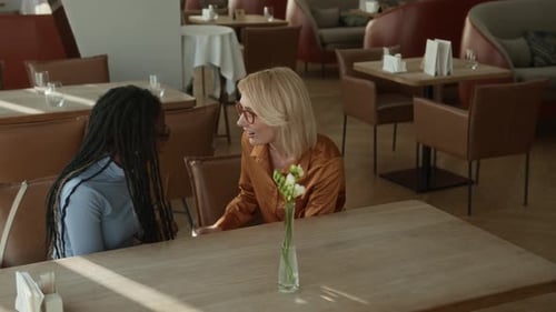 Diverse Girlfriends Chatting while Waiting for Meals in Restaurant