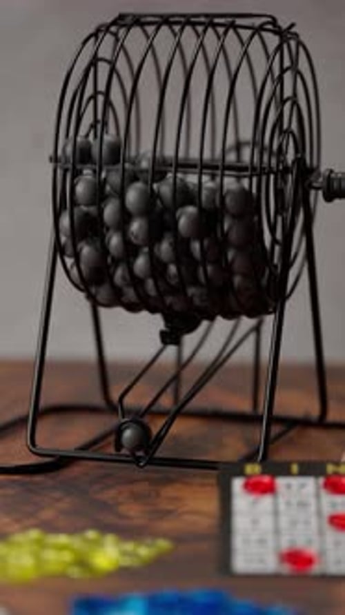 Vertical Video, Bingo Wheel Spinning With Grey Balls Inside And Coming Out Through The Ramp