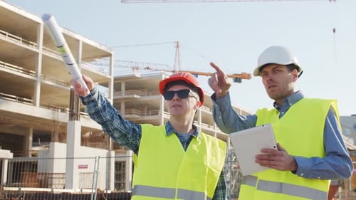 Professionelle Bauarbeiter stehen vor der Baustelle, dem Bürogebäude und dem Kran im Hintergrund