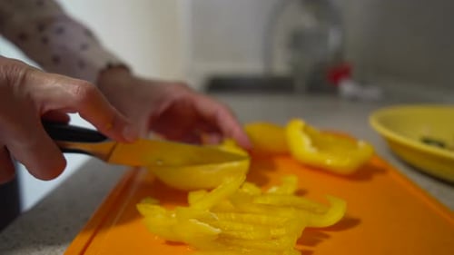 Hands Cutting Yellow Bell Pepper in Kitchen