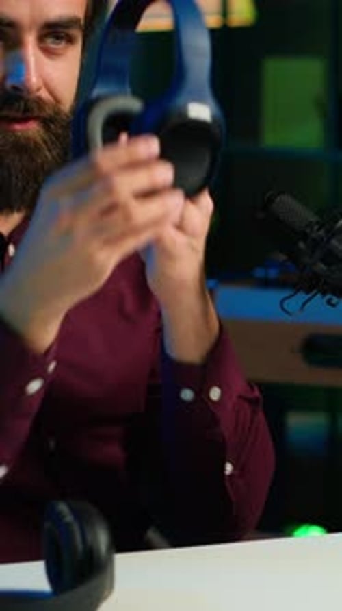 Man Puts On Headphones at Desk At Night