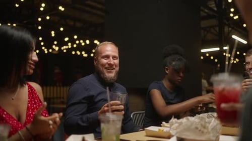 Friends Share a Meal and Drinks Outdoors at Night