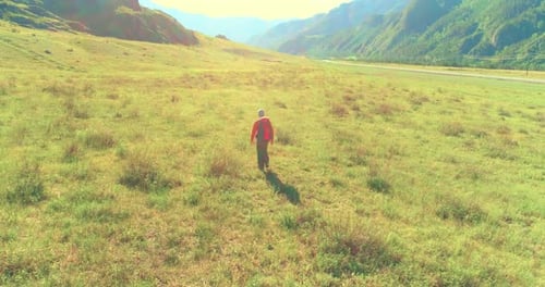 Flight Over Backpack Hiking Tourist Walking Across Green Mountain Field Huge Rural Valley at Summer