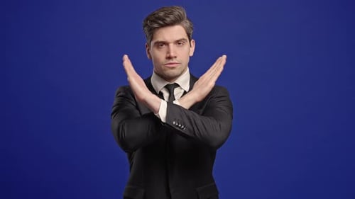 Man in Suit Poses with Arms Crossed in "X"