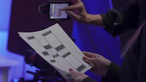 A Female Producer and a Male Cameraman Discuss the Storyboard in the Studio Storyboard Sheets in the