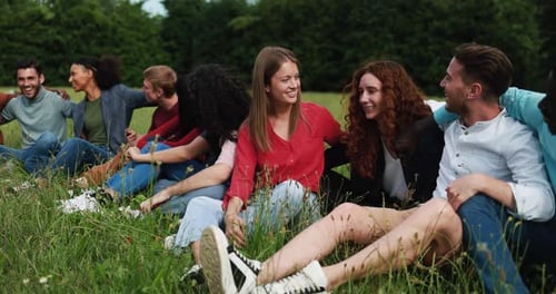 Multiethnic friends having fun sitting on grass outdoor
