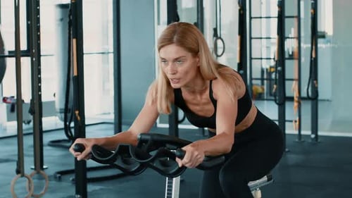 Woman With Light Skin Exercising on a Fitness Machine in a Modern Gym Setting