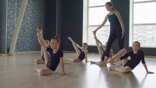 Teacher Helping Group of Gymnasts Practicing in Studio
