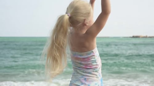 Happy Child Girl Dancing on the Beach Against the Backdrop of the Sea Slow Motion