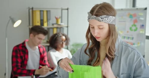 Una hermosa jovencita pone comida en una bolsa de papel ecológica con la inscripción La ecología llama a resolver el problema
